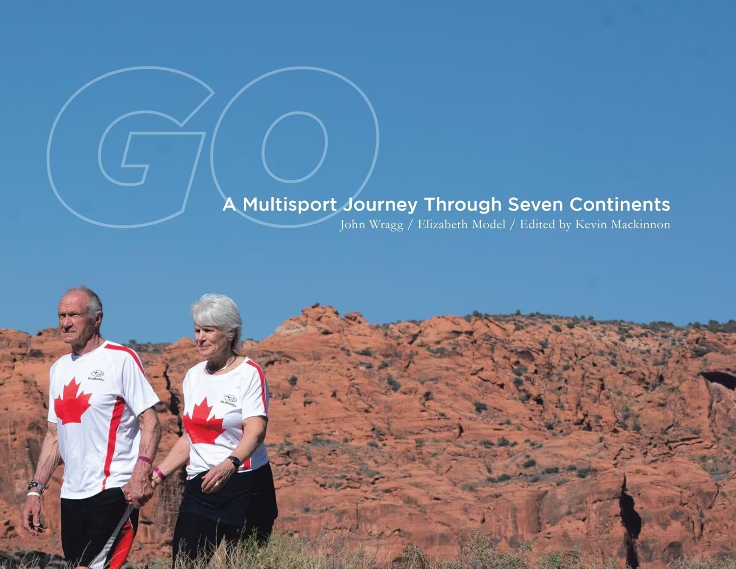 Elizabeth Model and John Wragg holding hands in front of the mounts. Cover for Go, a multisport journey through the seven continents book. 